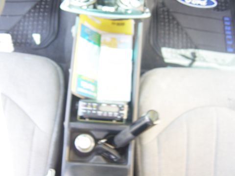 2000 Ford Crown Victoria - The interior of a car shows a center console with various items including a radio and papers.