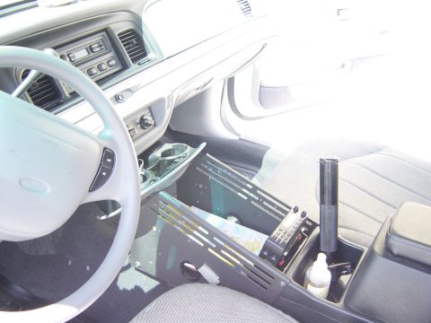 2000 Ford Crown Victoria - The interior of a police vehicle is shown, a radio and a map on the center console.