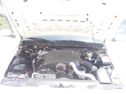 2000 Ford Crown Victoria - The engine bay of a white 2000 Ford Crown Victoria is shown with the hood open, revealing the V8 engine and associated components.