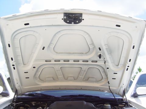 2000 Ford Crown Victoria - View of the underside of a white car hood, revealing structural bracing and the hood latch assembly.