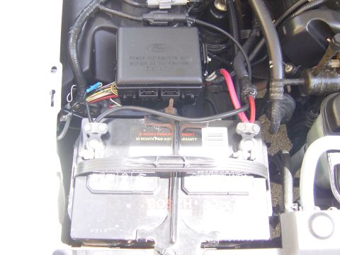 2000 Ford Crown Victoria - Close-up of a car battery and its associated power distribution box, showing electrical connections.