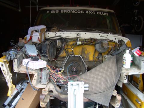 1978 Ford Bronco - The engine bay of a vehicle is shown with extensive wiring and components exposed, suggesting a repair or modification is in progress.