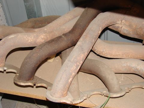 1979 Ford Bronco - Several old, rusty exhaust manifolds are piled on a shelf. A watermark for SuperMotors.net is visible.