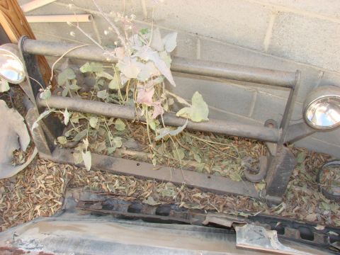 1979 Ford Bronco - A weathered front bumper assembly, partially obscured by weeds and debris, is visible in this image.