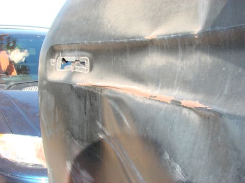 1979 Ford Bronco - A damaged black fender with a broken headlight housing is visible, with rust peeking through the damaged area.