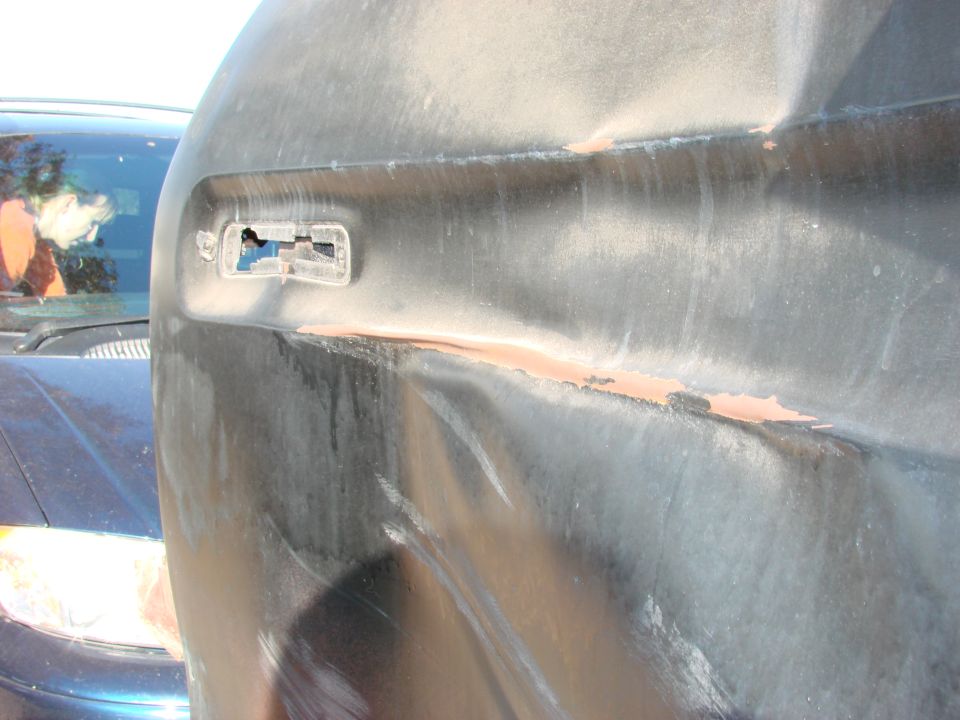 Damaged black fender with broken headlight housing and rust showing through