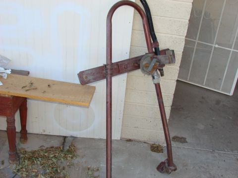 1979 Ford Bronco - A close-up of a rusty jack stand with hoses attached, resting on concrete.
