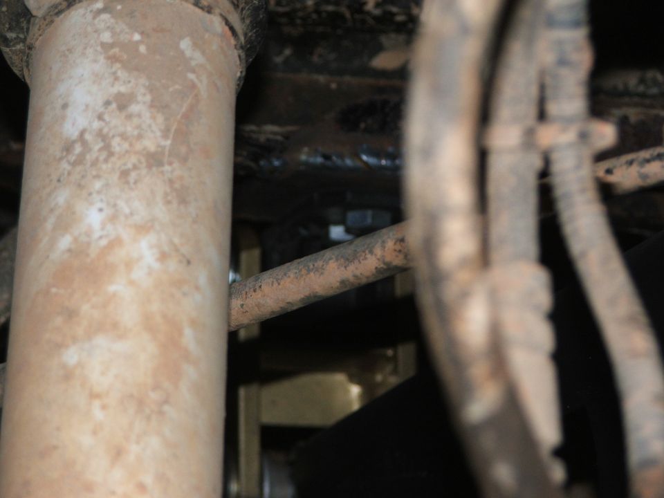 Close-up of rusty suspension parts and wiring harness on vehicle undercarriage