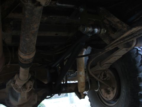 1996 Ford Bronco - Underside view of vehicle suspension components, showing driveshaft, leaf springs, and shock absorber.