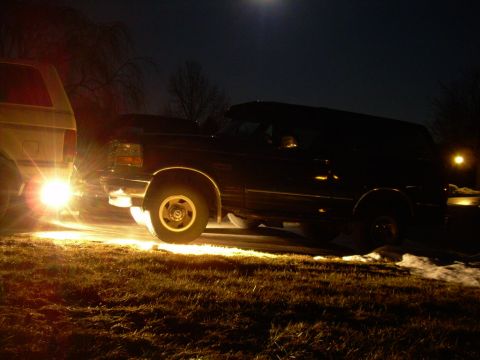 1988 Ford Bronco - Two SUVs are parked at night, with one vehicle's reverse lights illuminating the ground.
