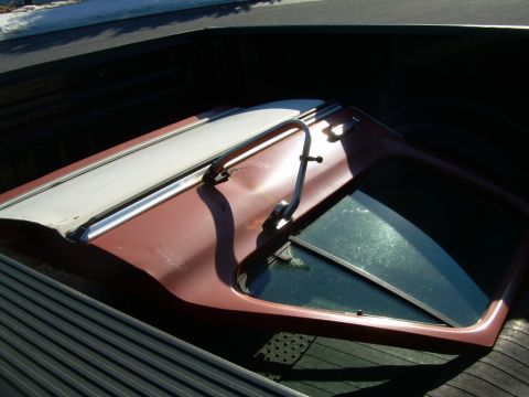 1997 Ford F-150 - Camper shell with a white top and red sides is loaded into the bed of a pickup truck.