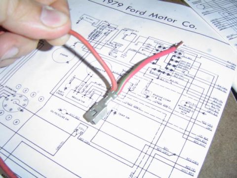 1979 Ford Bronco - A hand holds a red wire over a 1979 Ford Motor Co. wiring diagram.