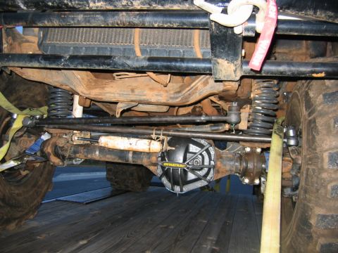 1992 Ford Mustang - The underside of a heavily modified off-road vehicle is shown, a Dynatrac differential cover and prominent yellow tie-down straps.
