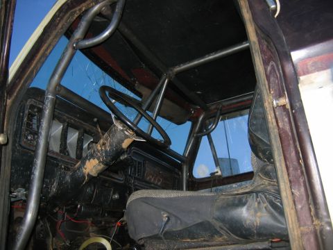 1992 Ford Mustang - The interior of a vehicle is shown with a prominent roll cage and a damaged windshield.