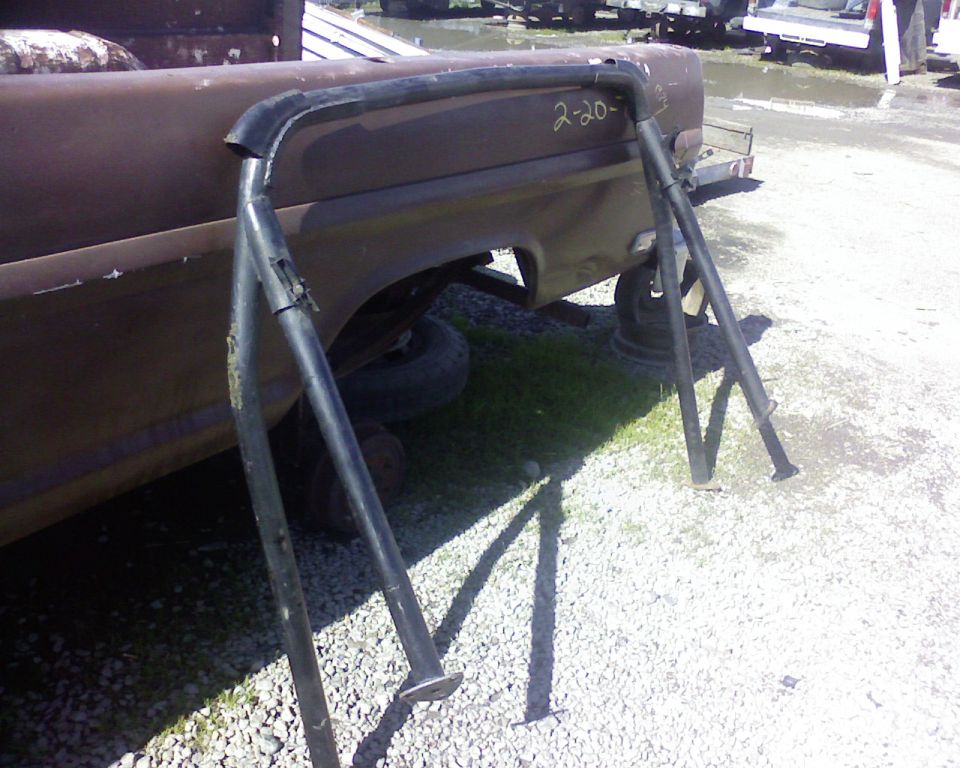 Roll bar with handwritten '2-20-' on a rusty truck bed