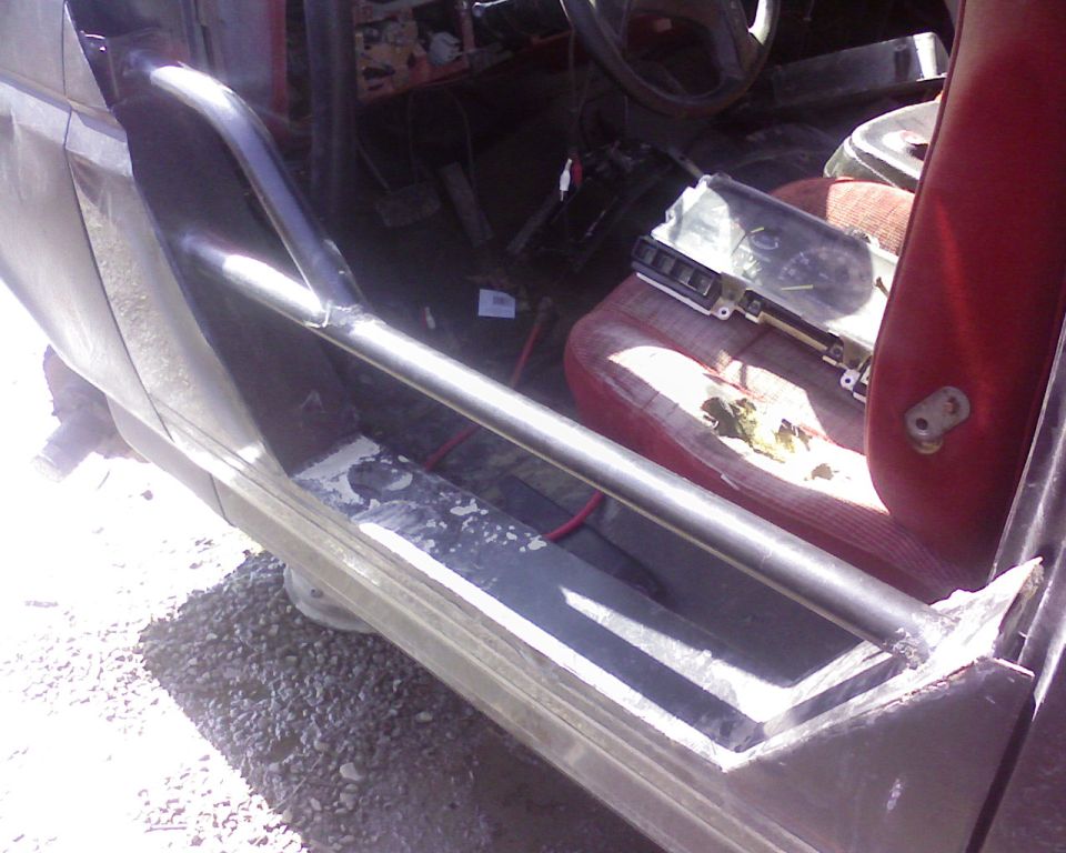 1995 Ford Bronco interior, driver's side, with roll cage, red seats, and removed dashboard