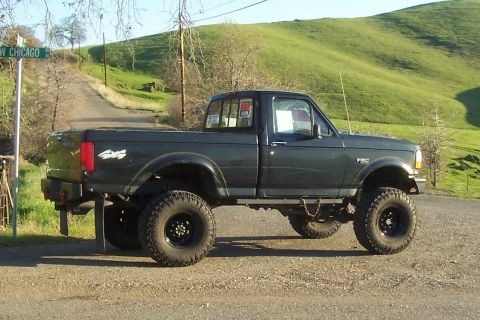 1994 Ford F-150 - This lifted 1994 Ford F-150 pickup truck is shown in a side profile view on a dirt road.
