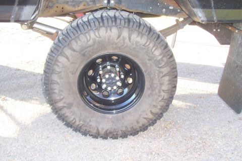 1994 Ford F-150 - Close-up of the rear wheel and suspension of a 1994 Ford F-150, showing an off-road tire and black rim.