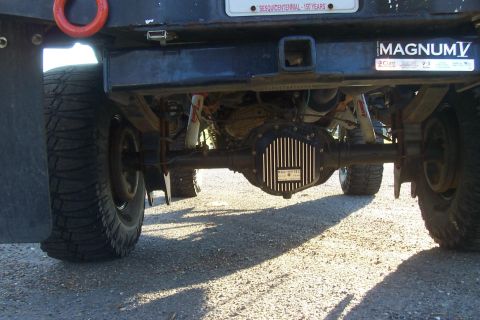1994 Ford F-150 - Close-up view of the rear axle and suspension components of a truck, showing aftermarket parts and a license plate.