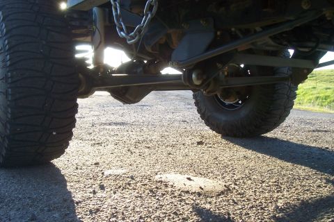 1994 Ford F-150 - The underside of a truck is shown, focusing on its heavy-duty suspension and large off-road tires.