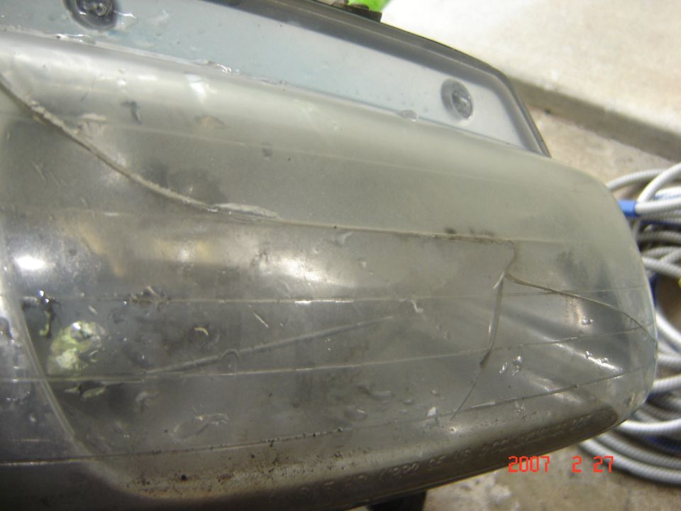 Close-up of a dirty, cracked headlight assembly with visible internal wiring