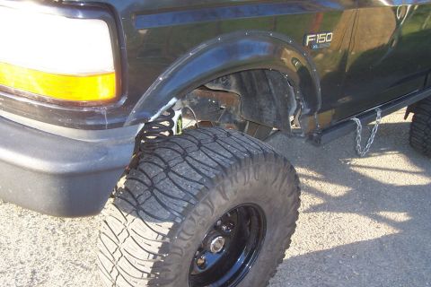 1994 Ford F-150 - Close-up view of the front fender, wheel, and F150 badge on a black 1994 Ford F-150 pickup truck.