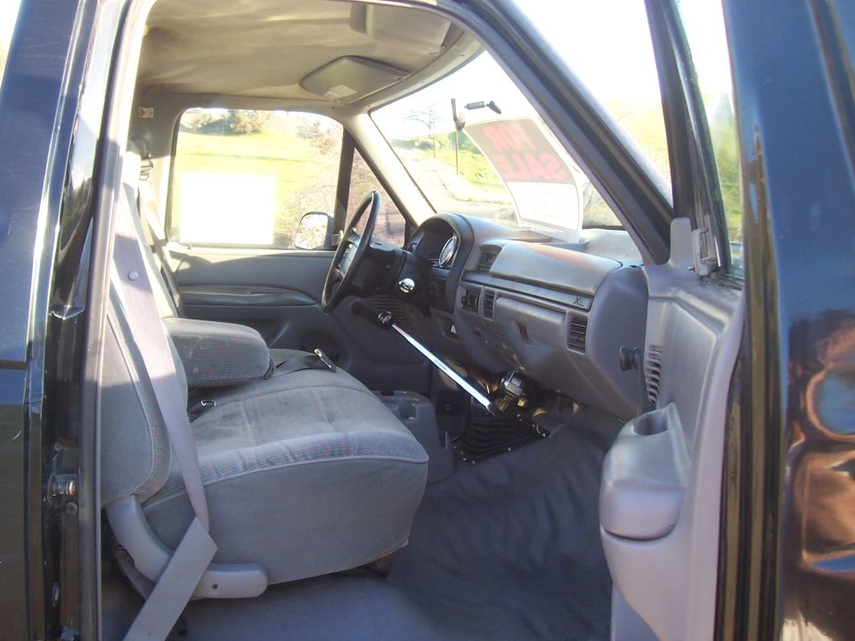 Interior of a dark blue 1992 Ford F-150 pickup truck, showing the driver's seat, dashboard, and floor shifter