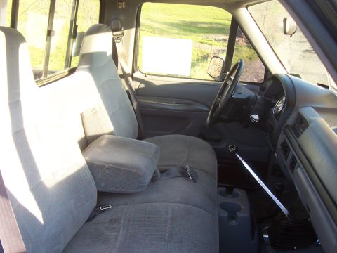 1994 Ford F-150 - The interior of a 1994 Ford F-150 features grey cloth seats, a center console, and a manual transmission shifter.