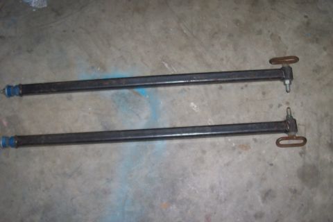1994 Ford F-150 - Two black metal bars with blue bushings and metal loops are shown on a concrete floor.