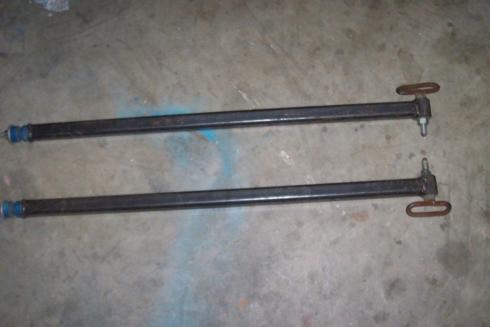 Two black metal bars with blue bushings and metal loops on a concrete floor