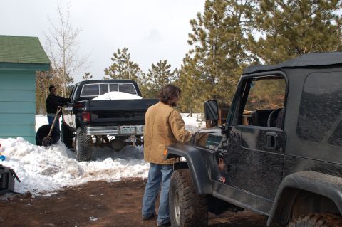 1985 Chevrolet C/K Pickup - Two trucks are parked in a snowy area with a person shoveling snow. The Chevrolet C/K Pickup appears to be from the 1980s.