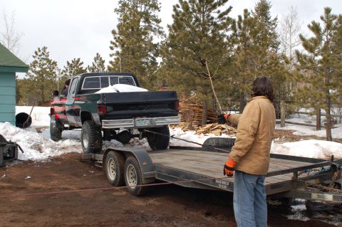 1985 Chevrolet C/K Pickup - A black 1985 Chevrolet pickup truck with a red stripe is loaded onto a trailer in a snowy environment.