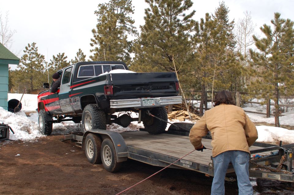 1985 Chevrolet C/K Pickup being winched onto a trailer, lifted suspension, red and black paint scheme