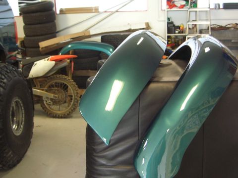 1996 Ford Bronco - Two green fenders are displayed in a workshop setting, with a motorcycle and tires visible in the background.