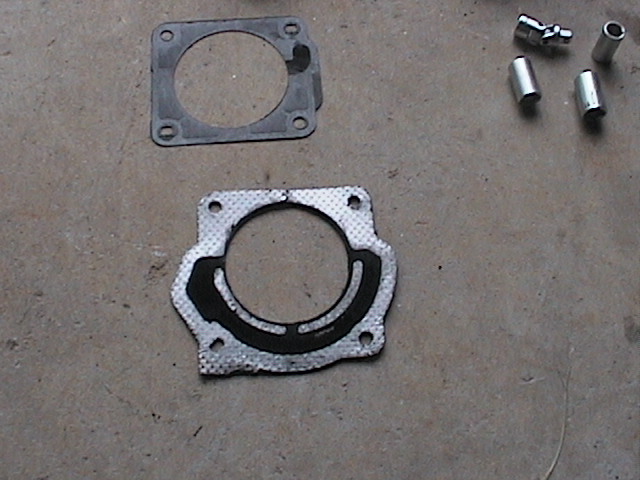 Two gaskets and four pieces of hardware on a concrete surface