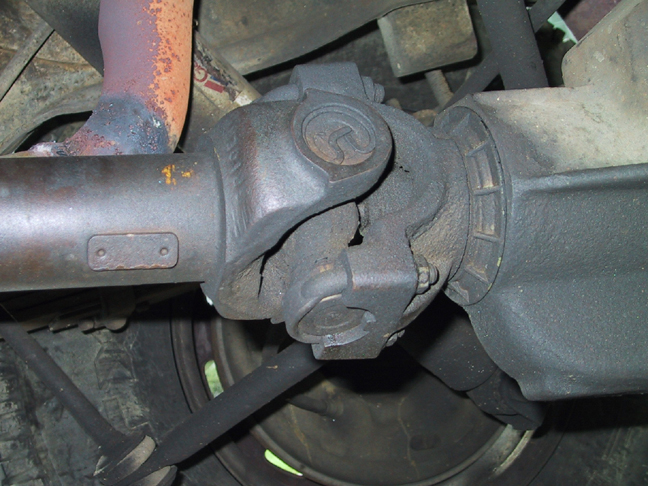 Greasy, rusty driveshaft slip yoke and U-joint at the differential, viewed from under the truck