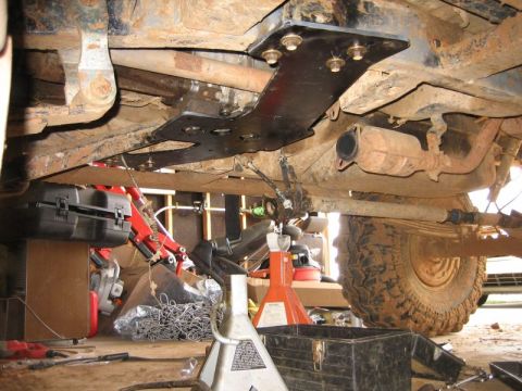 1986 Ford F-150 - The undercarriage of a truck shows a newly installed skid plate, with various tools and equipment around.