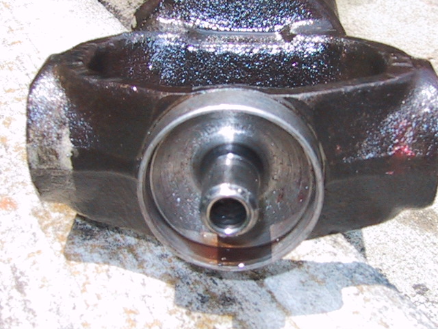 Close-up of greasy cast axle yoke end with machined bore and hollow center stub