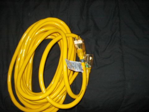 1991 Ford Bronco - A bright yellow extension cord is coiled on a dark surface, showing its plugs and a product label.