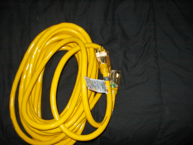 Coiled yellow extension cord with clear male and female ends. A white label is attached to the cord