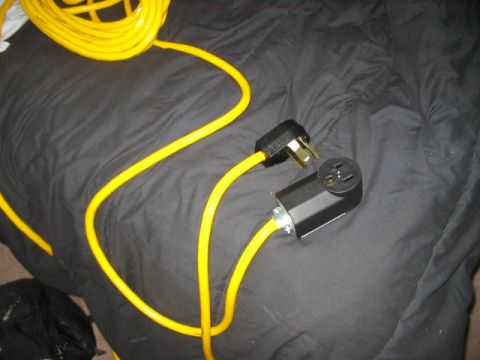 1991 Ford Bronco - A close-up view of a yellow extension cord connected to an adapter, lying on a dark surface.