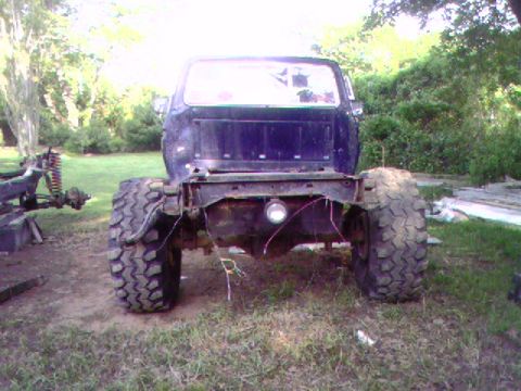1977 Ford F-250 - This dark blue pickup truck chassis is missing its bed and features large off-road tires, suggesting a custom build or restoration project.