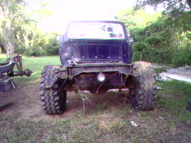 Rear view of a dark blue pickup truck chassis with large off-road tires and no bed