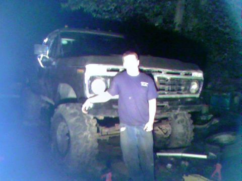 1977 Ford F-250 - Person stands next to a lifted 1977 Ford F-250 pickup truck with large off-road tires.
