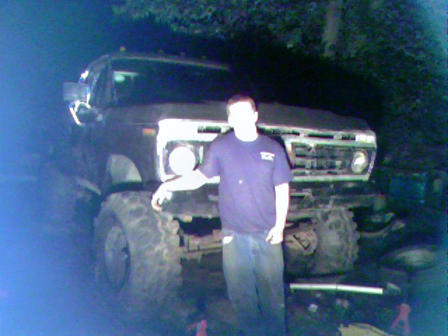 1977 Ford F-250 pickup truck with large tires and a person standing beside it