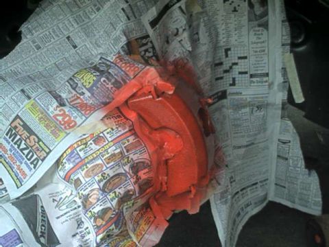 1976 Ford Ranchero - A red painted brake caliper is shown wrapped in newspaper pages, obscuring any vehicle details.