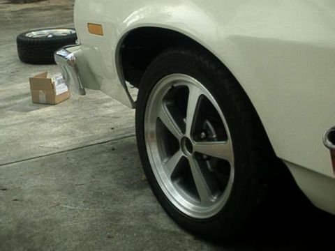 1976 Ford Ranchero - A white vehicle's side profile is visible, with a spare tire and a small box on the ground.