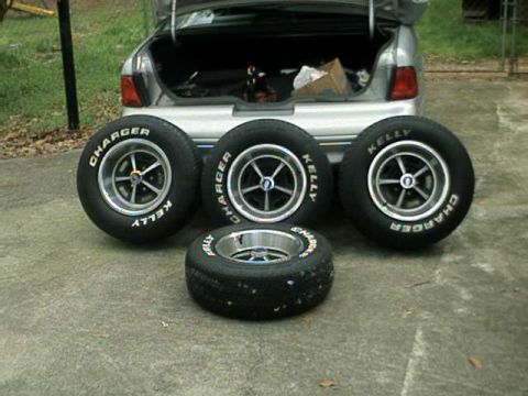 1976 Ford Ranchero - Four tires are arranged in front of the open trunk of a car. The tires are labeled 'Kelly Charger'.