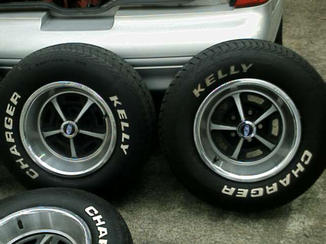 Three Magnum 500-style wheels with Ford center caps on Kelly Charger white-letter tires