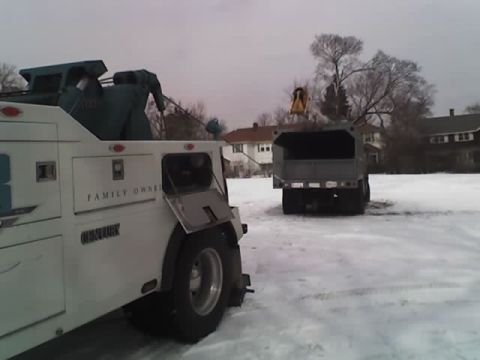 1992 Ford Bronco - A tow truck and a dump truck are parked in a snow-covered area, with houses visible in the background.
